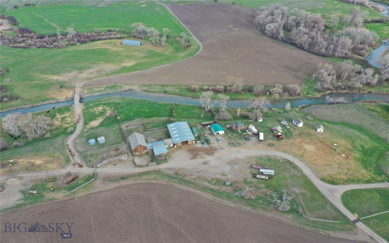 Aerial view of outbuildings, Sweetgrass Creek, tilled fields, and pasture. On the 295 acre parcel.